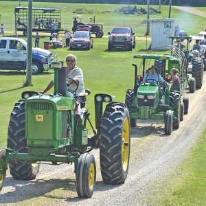 LEADER OF THE PACK — Ken Maes (in front) of Glenwood City led the 8th annual St. Croix County Fair Tractor Caravan last Saturday morning, July 10 as it left the fairgrounds for a scenic 26-mile drive around the Glenwood City area. The annual caravan kicks off the St. Croix County Fair which runs July 14-18 this year. More than 30 tractors and over one hundred people participated in the event that went up Oak Street and visited residents at Glenhaven, Grand Oaks, and Havenwood on its way out of town. Maes took over coordinating and organizing the event which has becomea tradition that was orginally started by Dick and Gayle Sullwold. Dick Sullwold is piloting the tractor behind Maes. —photo by Carole Schurtz