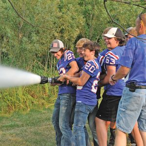 Members of the Glenwood City Football team struggle to hold a large fire hose. The display was part of the local fire departments participation in the National Night Out event. —photo by Carlton DeWitt