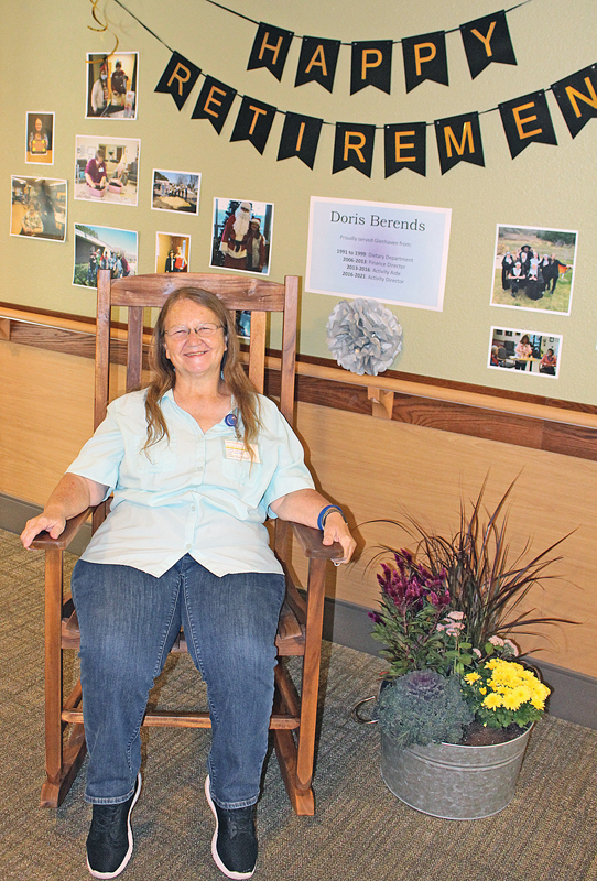 RETIREMENT GIFT — Doris Berends shown sitting in front of her retirement display, testing out the rocking chair presented to her by Glenhaven. —photo by Missy Klatt