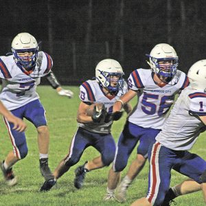 PLENTY OF HELP — Topper running back Max Janson (#10 in center) received plenty of blocking support on this carry as teammates Gabe Knops (#7), Thomas Moede (#56), and Brady McCarthy (#1) looked to clear a path to run. Janson finished with 177 yards and three touchdowns to lead Glenwood City to a 31-13 win in Cadott October 1. —photo by Joel DeWitt